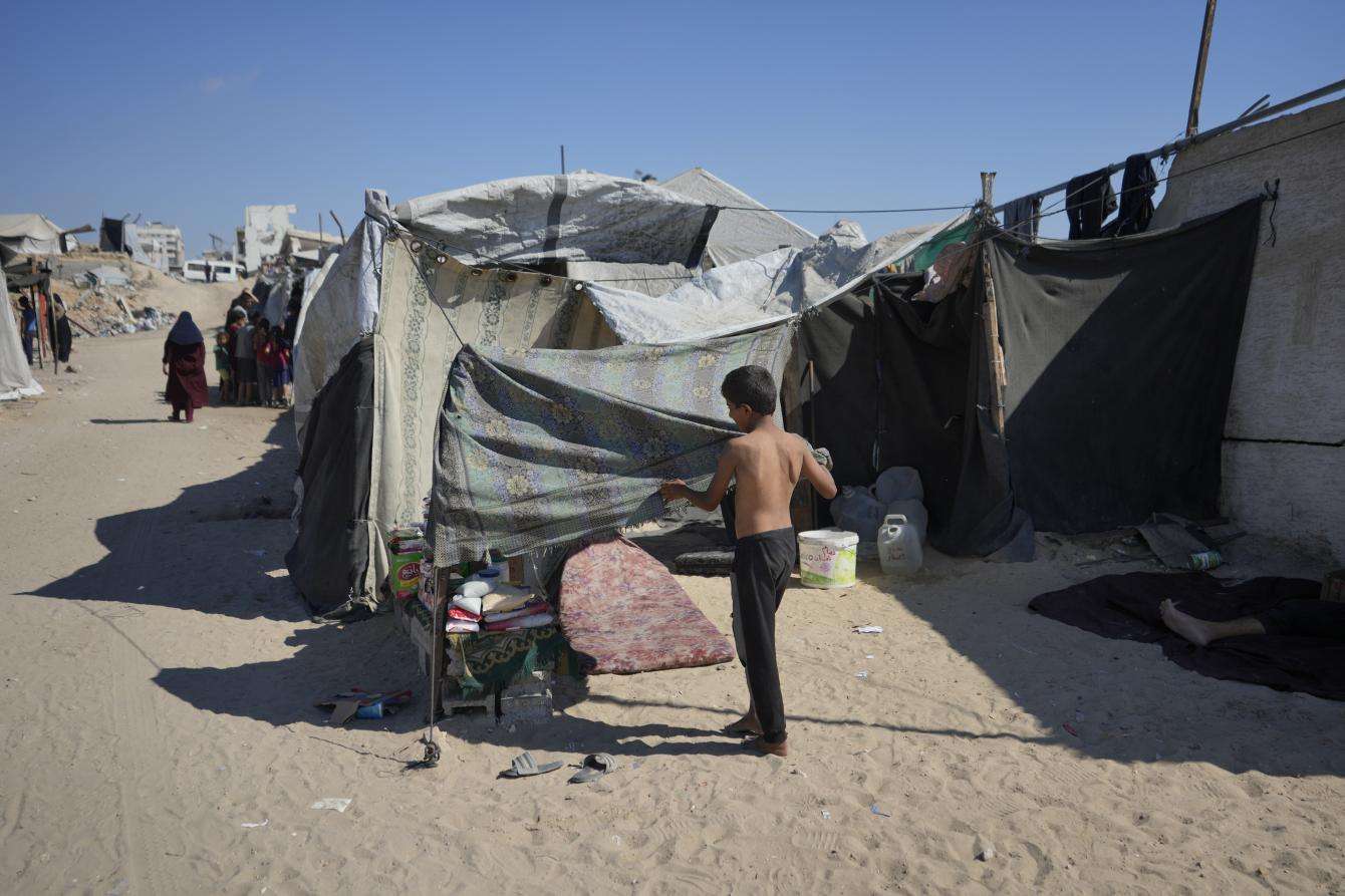 A boy stands in front of a tent in Gaza City, Palestine. 