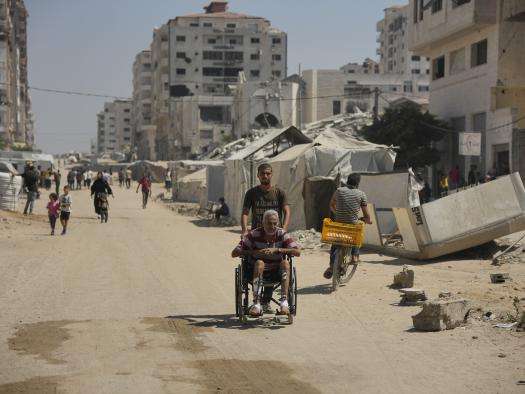 A man pushes an elderly man in a wheechair in Gaza City. 