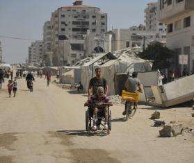 A man pushes an elderly man in a wheechair in Gaza City. 