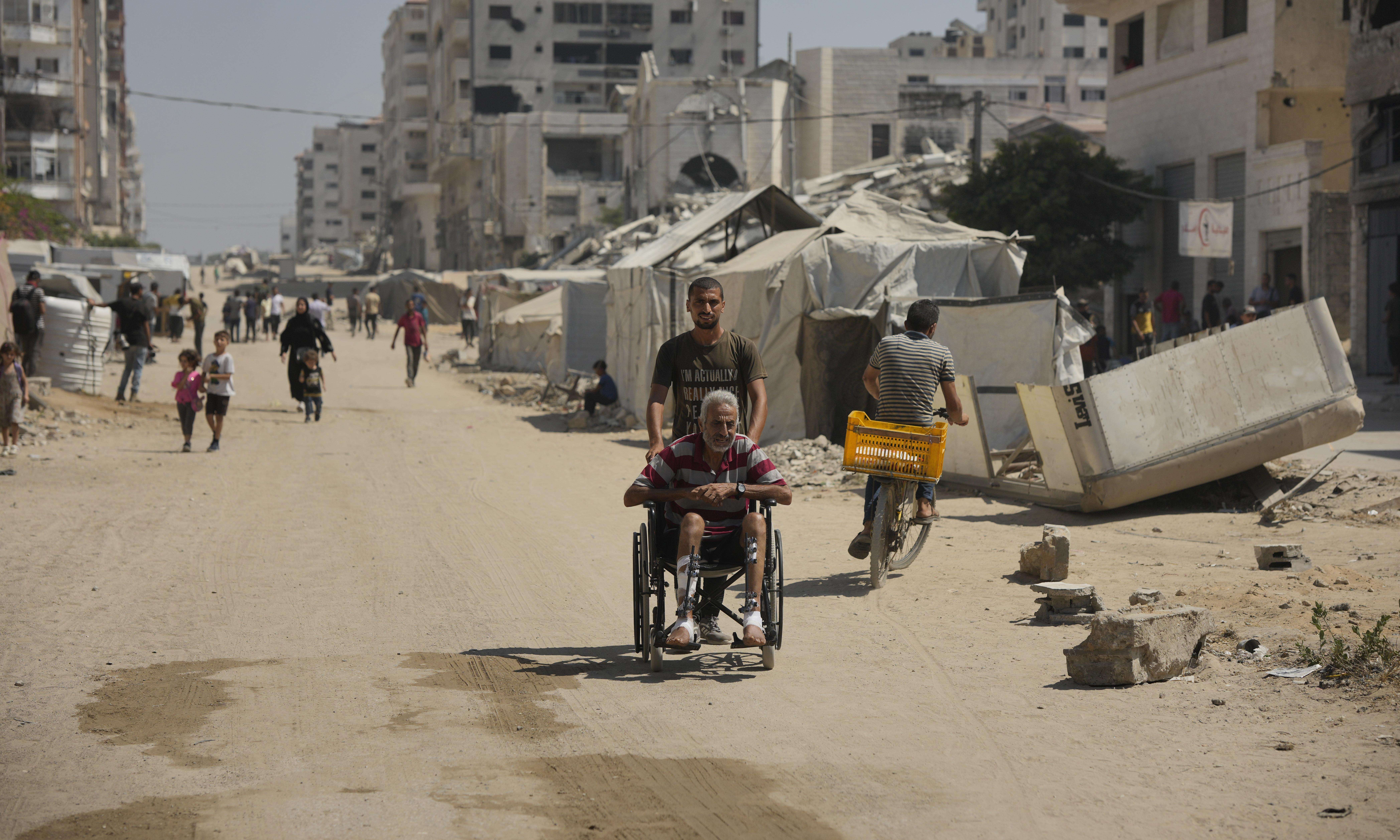 A man pushes an elderly man in a wheechair in Gaza City. 