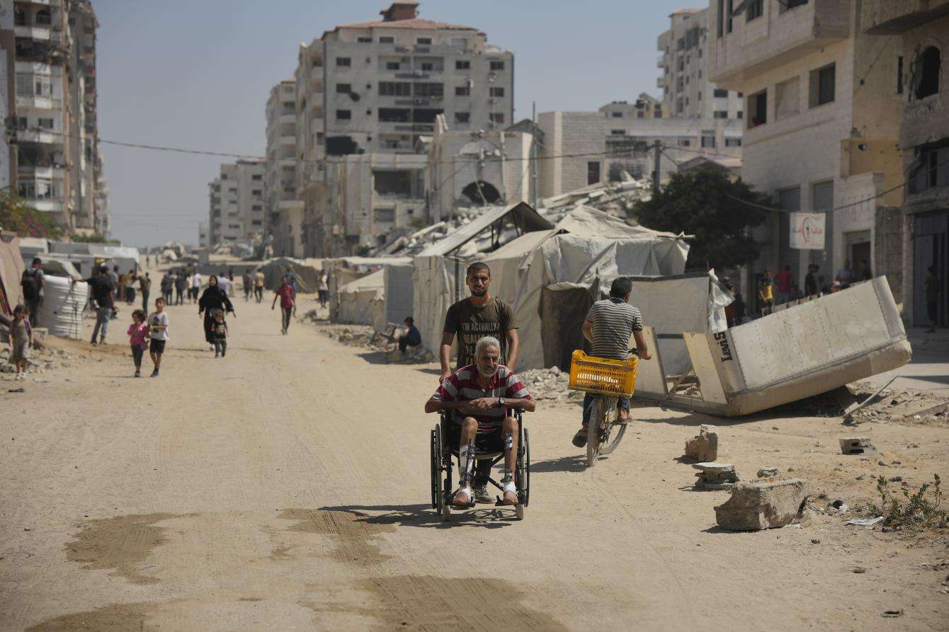 A man pushes an elderly man in a wheechair in Gaza City. 