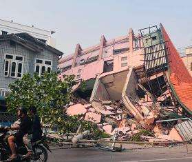 People ride on a motorbike past a destroyed building in Myanmar. 