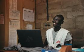 An MSF communications manager smiles while working at a computer.