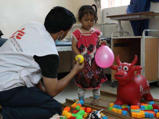 A mental health counselor in Yemen shows a girl a pink balloon. 