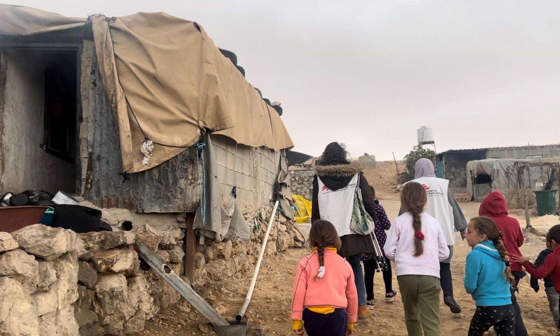 An MSF staff member walks in the street with children in Masafer Yatta, Palestine. 