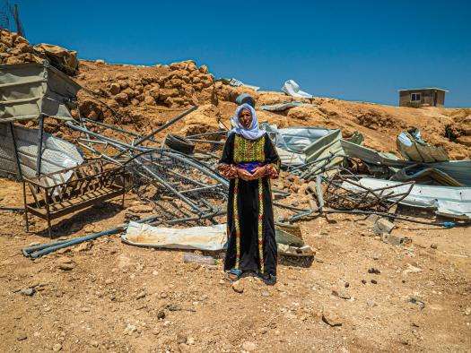 A woman stands before the rubble left of her home after it was demolished by Israeli forces in Masafer Yatta, West Bank.