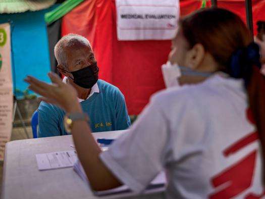 A patient sits at a table in front of an MSF staff member for a free X-ray at an MSF tuberculosis (TB) screening sites in Manila.