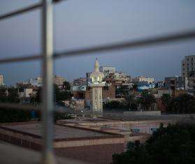 View of an urban landscape in Sudan through the bars of a fence.