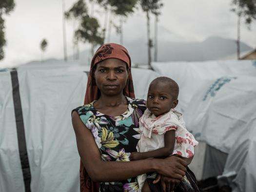 A woman holding a baby in a makeshift camp near Goma, Democratic Republic of Congo