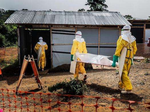 MSF staff members carry a deceased Ebola patient to the morgue in Kailahun, Sierra Leone. 