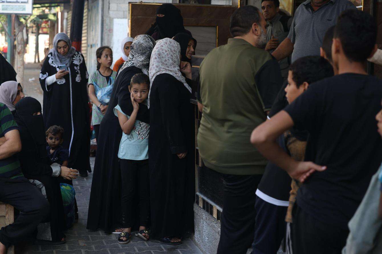 Palestinians line up for food and water in Gaza during the war with Israel in October 2023.