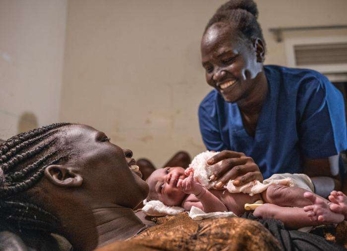 A patient in Aweil holds her daughter safely.