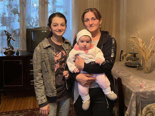 A family displaced from Nagorno-Karabakh stands in a home in Armenia where they are sheltering.