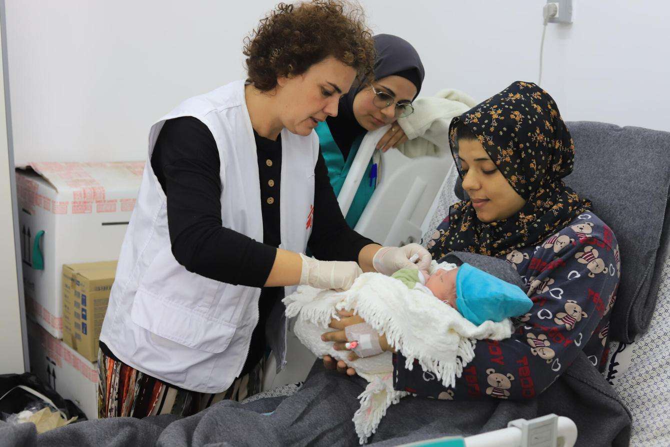MSF medical staff discussing with patient and checking on newborn child in the Emirati hospital, Rafah, southern Gaza.