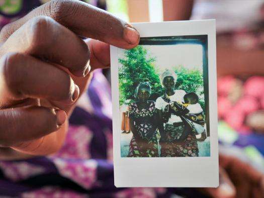 A woman holds a polaroid photo of a family in Mozambique.