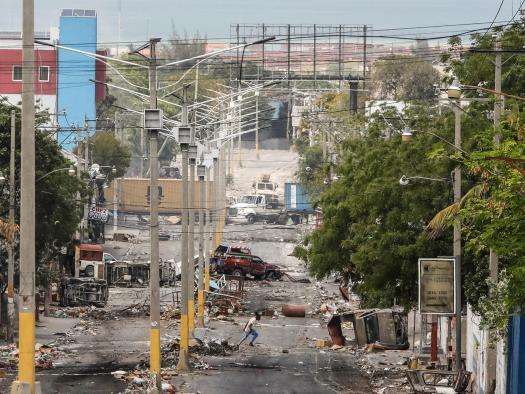 A man crosses the street in Haiti amid ruins from violent clashes. 