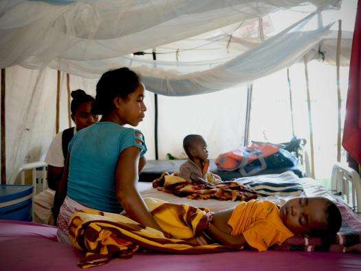 Mother sits beside her child receiving treatment for malaria.