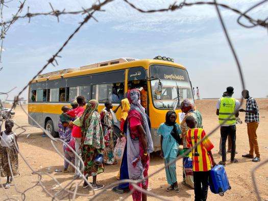 Returnees and refugees board a bus that will take them from the Joda border point to Renk transit center.
