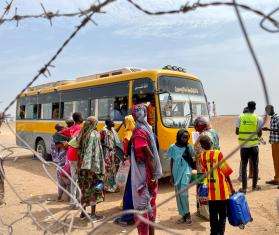 Returnees and refugees board a bus that will take them from the Joda border point to Renk transit center.