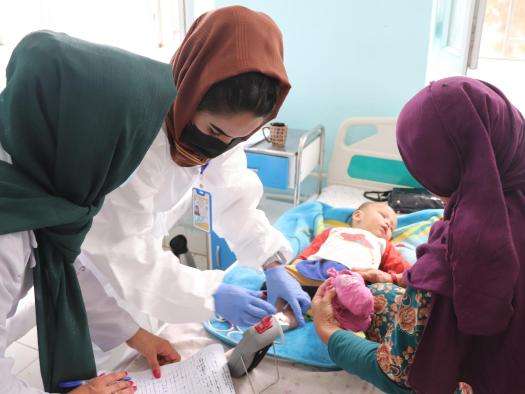 Three nurses care for a child with measles in Afghanistan. 