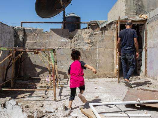 A Palestinian girl runs across rubble on her roof in the West Bank.