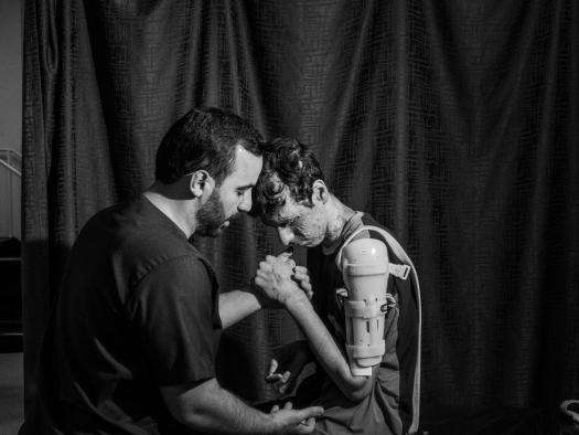 A patient with a braced shoulder receives therapy in a MSF hospital in Amman. 