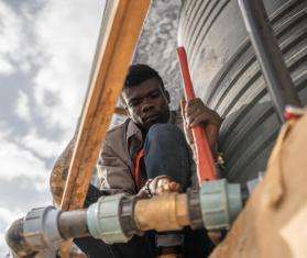 Water and sanitation supervisor Serge Bakor Lambey installs hoses to fill water tanks in Adré transit camp.