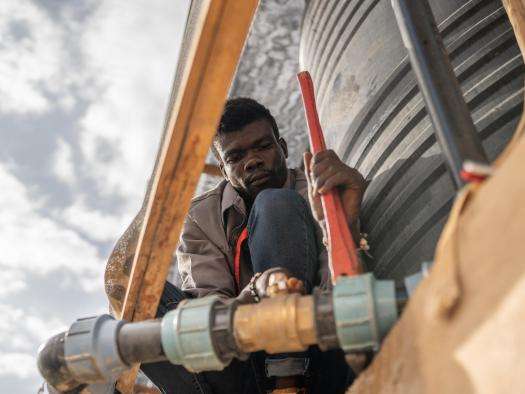 Water and sanitation supervisor Serge Bakor Lambey installs hoses to fill water tanks in Adré transit camp.