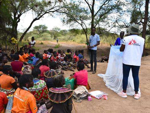 A health promoter holds a mosquito net in Kenya. 