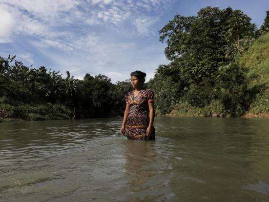A woman stands in the middle of a river in Colombia.