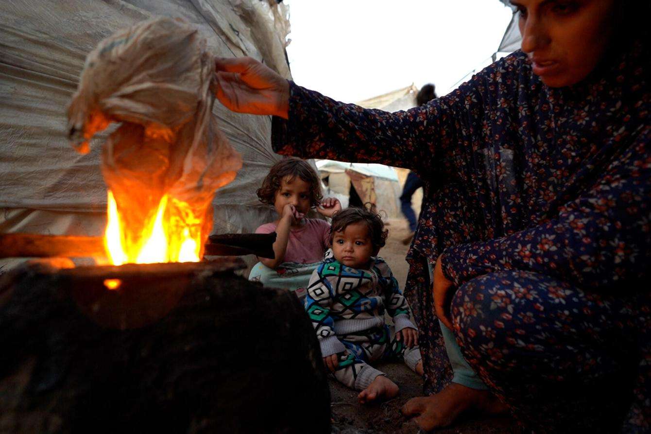 A mother lights a fire to cook in Gaza. 