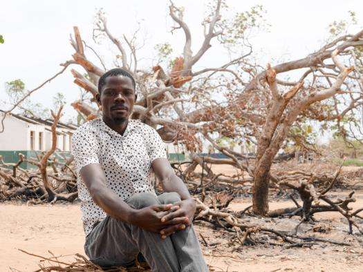 A displaced man sits in front of a tree in Mozambique. 