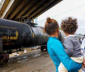 A woman holds a child next to train tracks in Mexico.