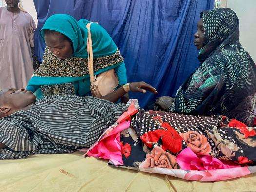 A patient sits with family members at Al Nao Hospital in Sudan. 