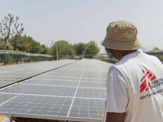 An MSF staff member stands in front of solar panels in Nigeria.
