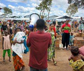 An MSF worker speaks through a megaphone to a crown in Burundi. 