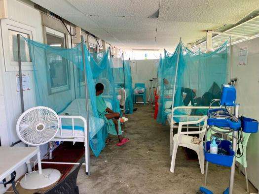A patient sits on a bed in the hallway of a hospital in Haiti. 
