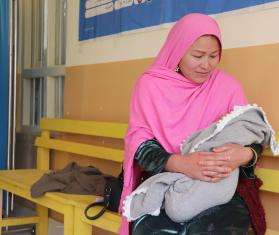 A seated woman holds a newborn in Afghanistan. 