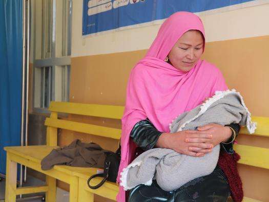 A seated woman holds a newborn in Afghanistan. 