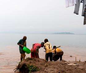 Men pan for gold next to a lake in DR Congo. 
