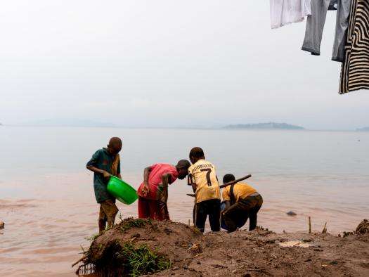 Men pan for gold next to a lake in DR Congo. 