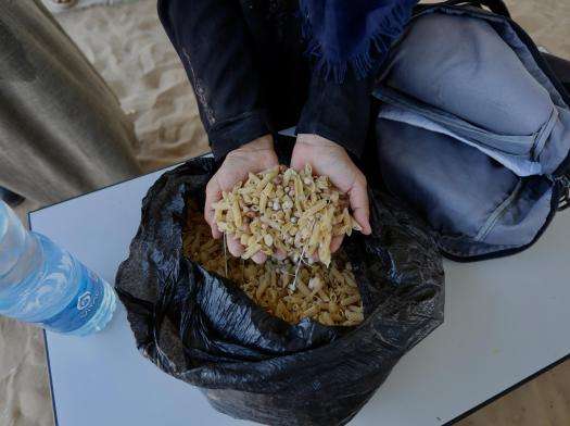 A Palestinian woman holds a handful of food from a distribution after risking her life to receive it in Gaza.