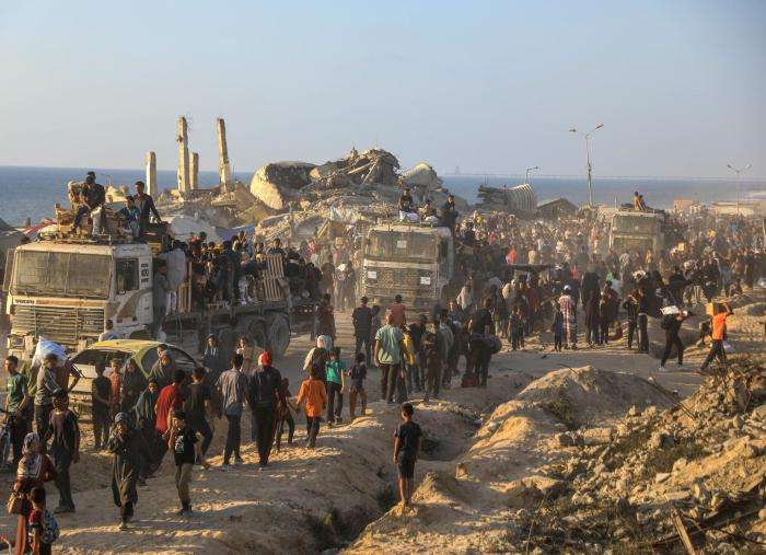 People line up next to trucks filled with armed guards to receive aid in Gaza. 