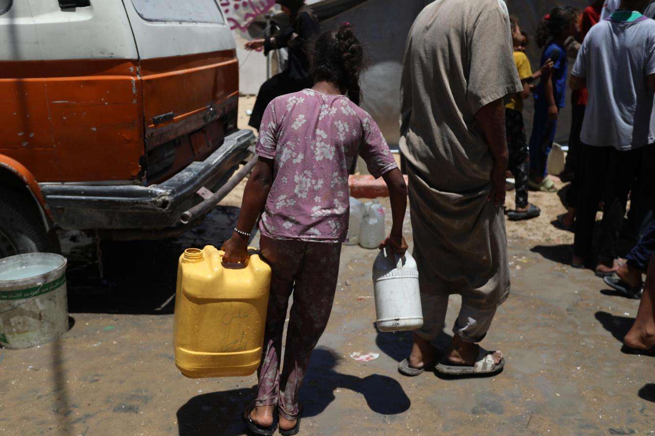 A girl carries a jerrycan to a water distribution point in Gaza, Palestine. 