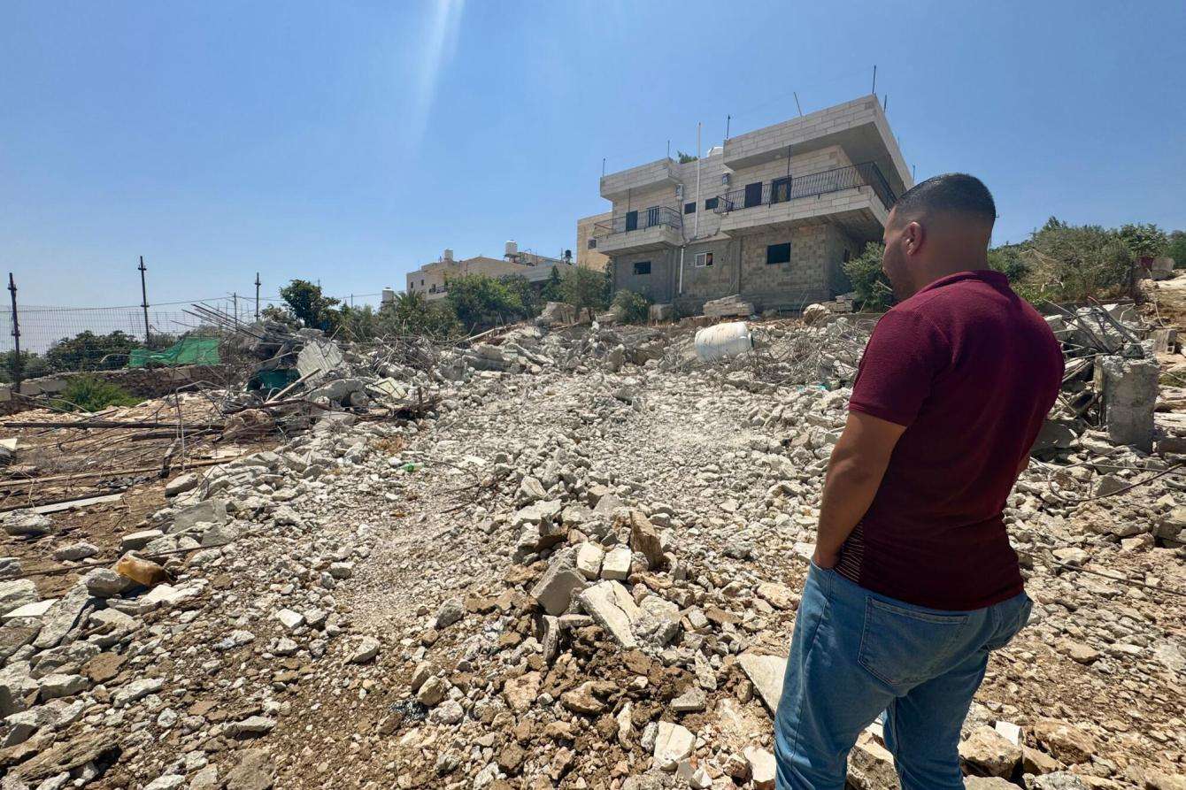 A man stands next to the ruins of his home in the West Bank, Palestine. 