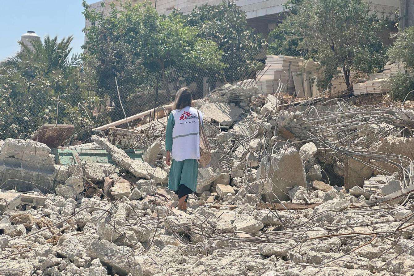 A staff member looks at the ruins of a Palestinian family home that was destroyed by Israeli forces. 