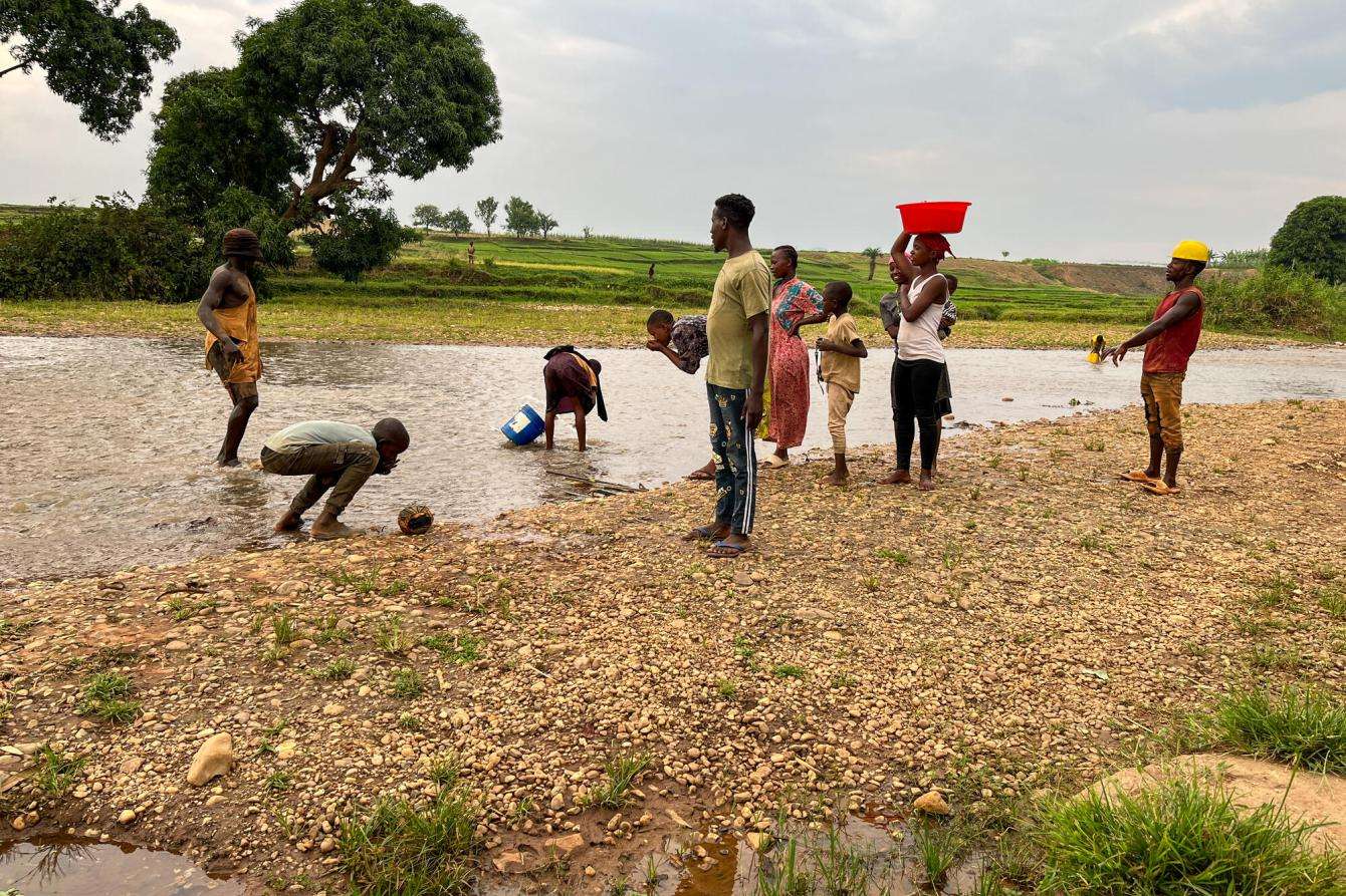People gather water from a river in Burundi. 