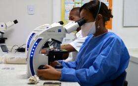 An MSF laboratory specialist examines a specimen under a microscope.