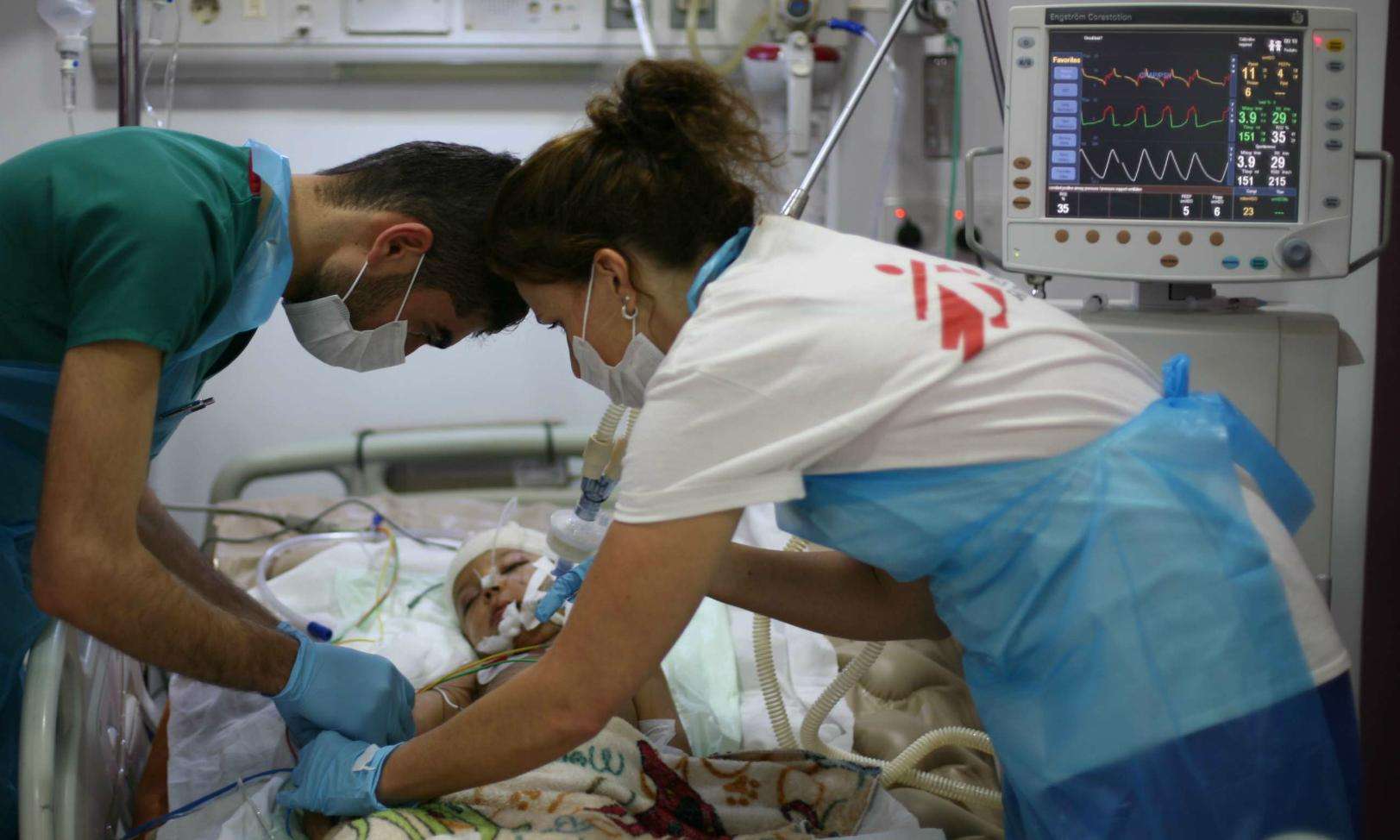 Two MSF staff members providing medical care to a child patient in critical condition