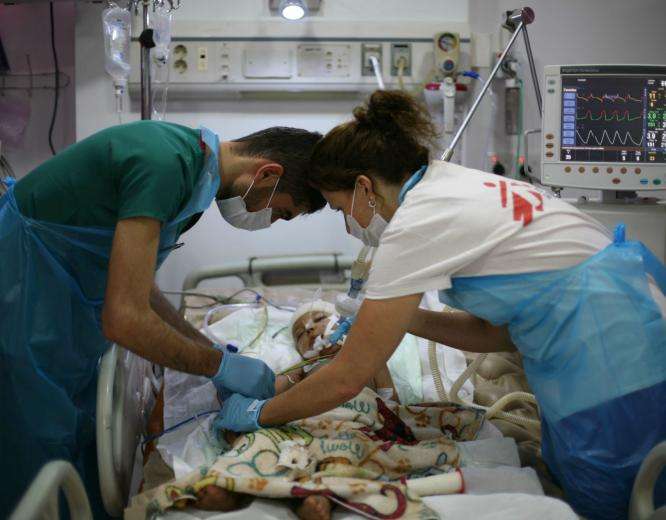 Two MSF staff members providing medical care to a child patient in critical condition